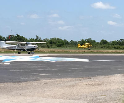 White airplane in foreground and yellow airplane taking off in background